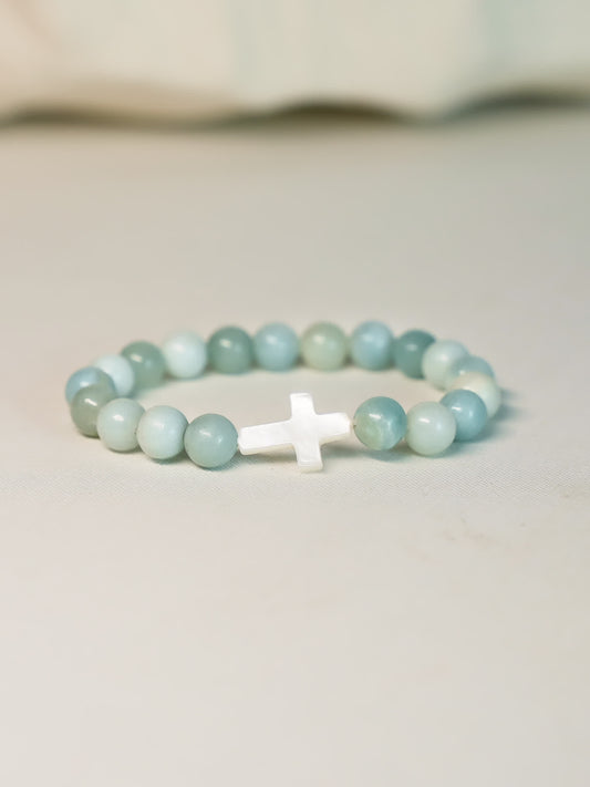Front-facing product shot of the Sea of Grace Cross Bracelet on a clean neutral background, showcasing the cross and ocean-toned gemstone beads.