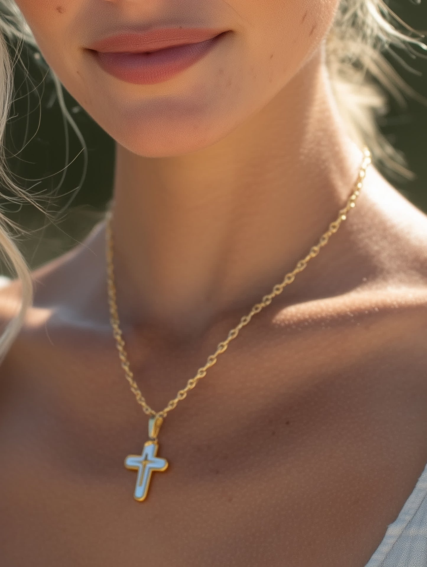Close-up lifestyle shot of a woman wearing the white enamel cross necklace outdoors
