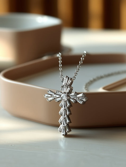 Lifestyle product shot on table: Sparkling crystal cross necklace with floral pattern displayed upright on beige ceramic tableware