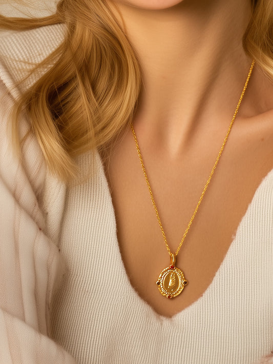 Close-up of the Virgin Mary medallion necklace worn by a woman in a cream sweater