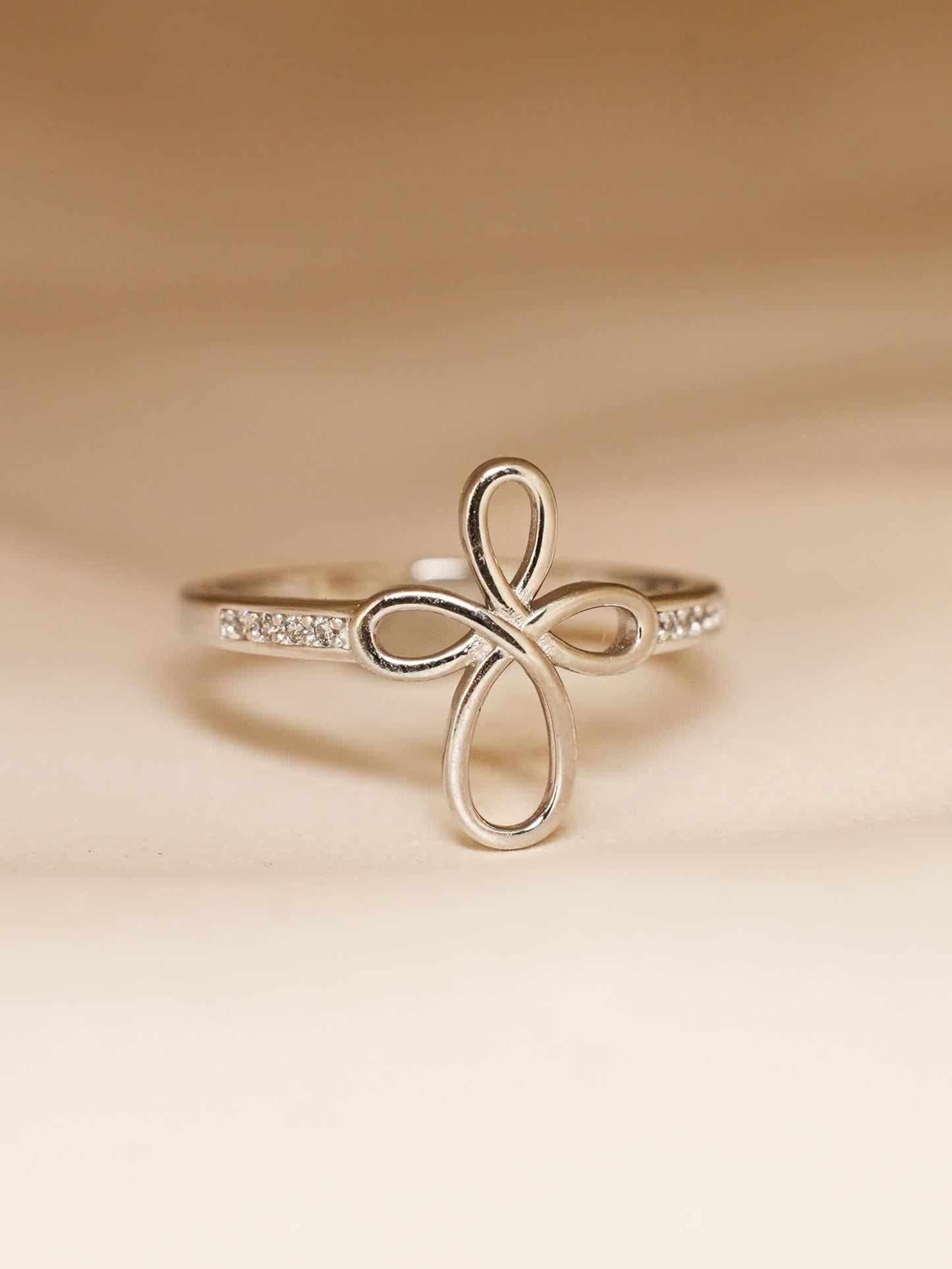 Covenant Bloom Ring worn on hand, highlighting the delicate silver heart cross shape and sparkling band in natural lighting