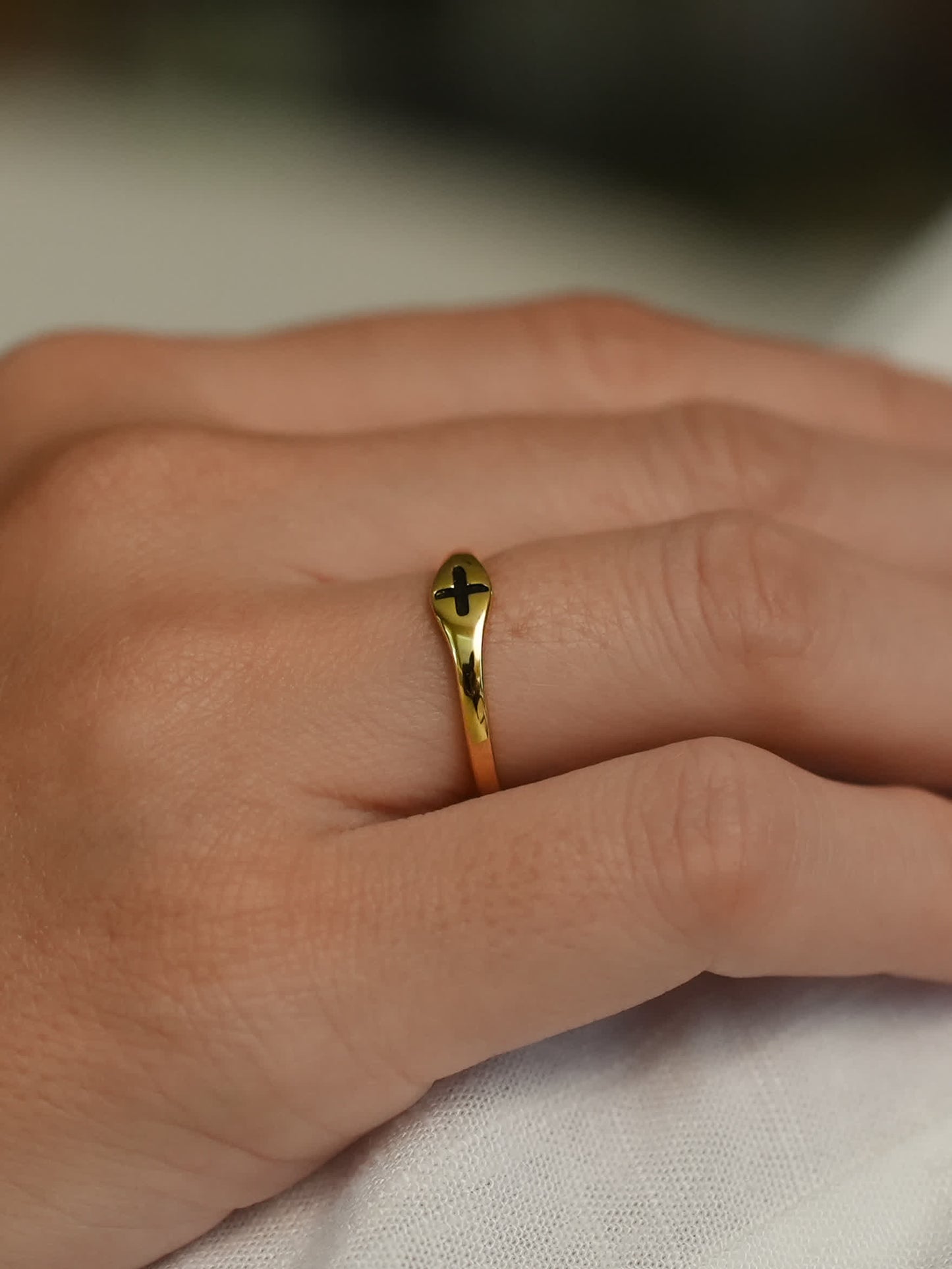 Close-up of Christian gold ring with black cross worn on finger, showcasing elegant fit and shine