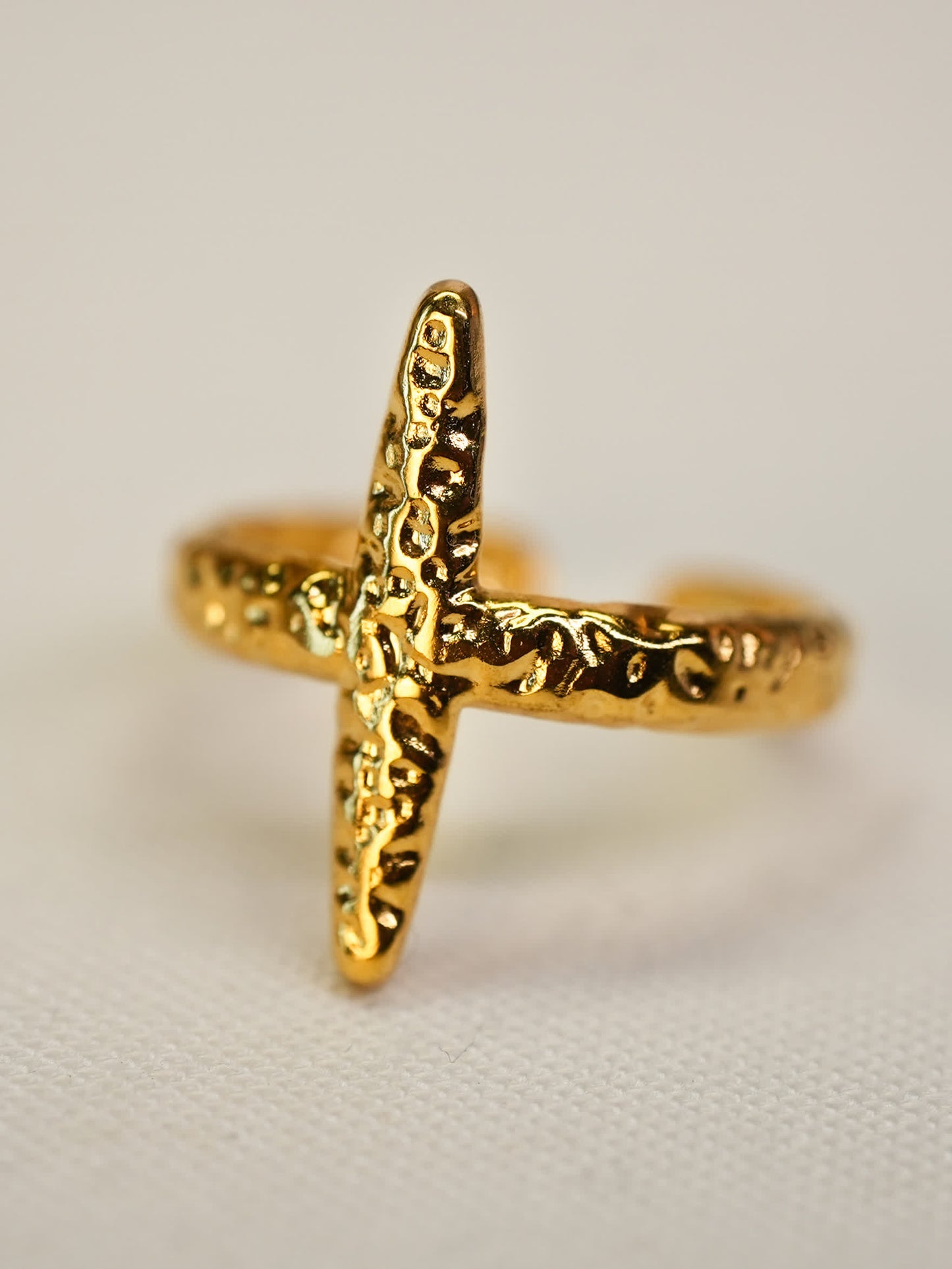 Close-up angled side view of hammered gold cross ring
