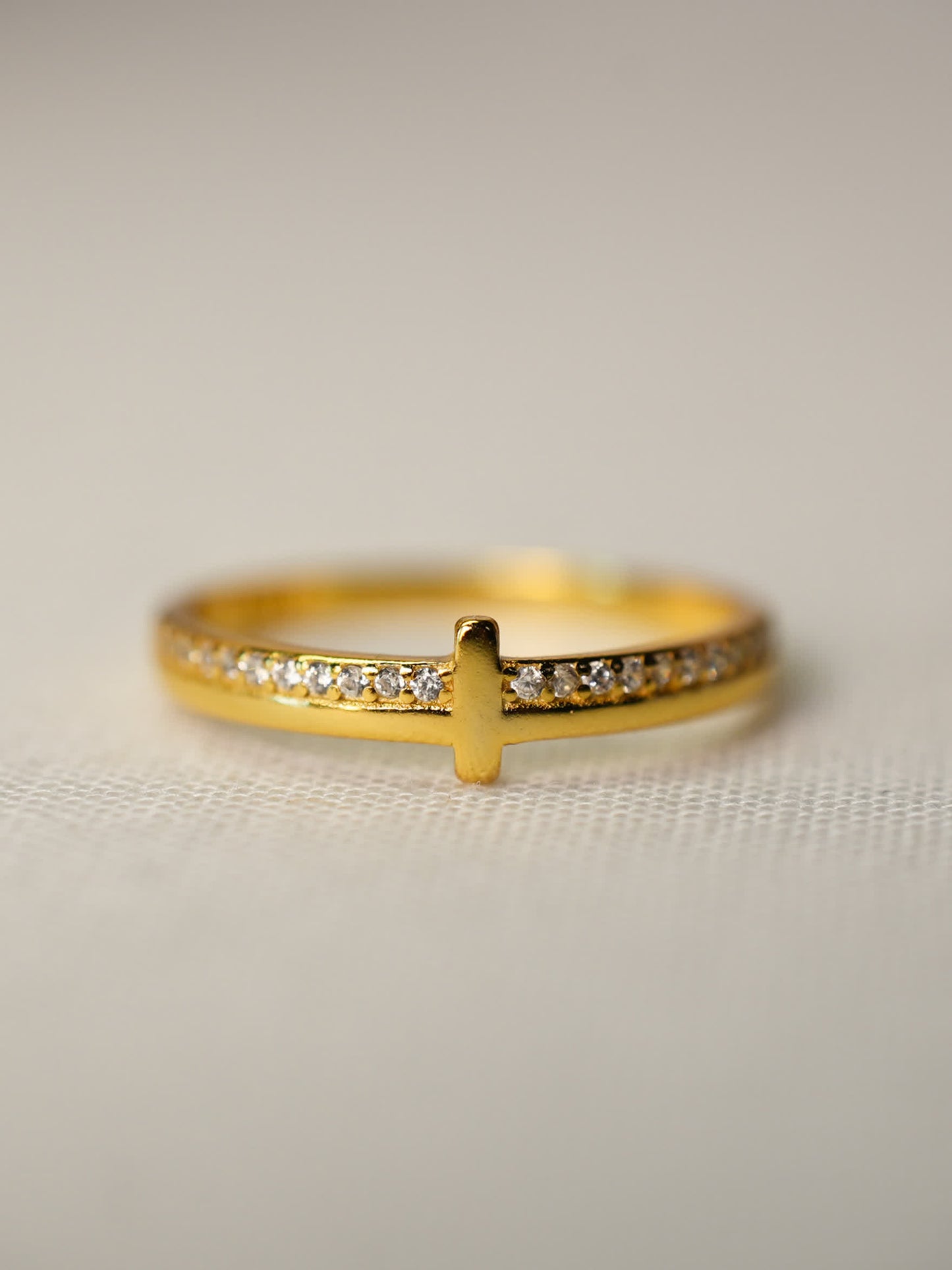 Elegant gold cross ring displayed flat with sparkling stone band