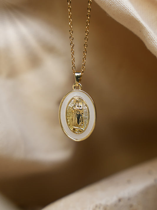 Close-up photo of the Madonna necklace hanging in a seashell with soft natural light highlighting the gold and shell inlay details.