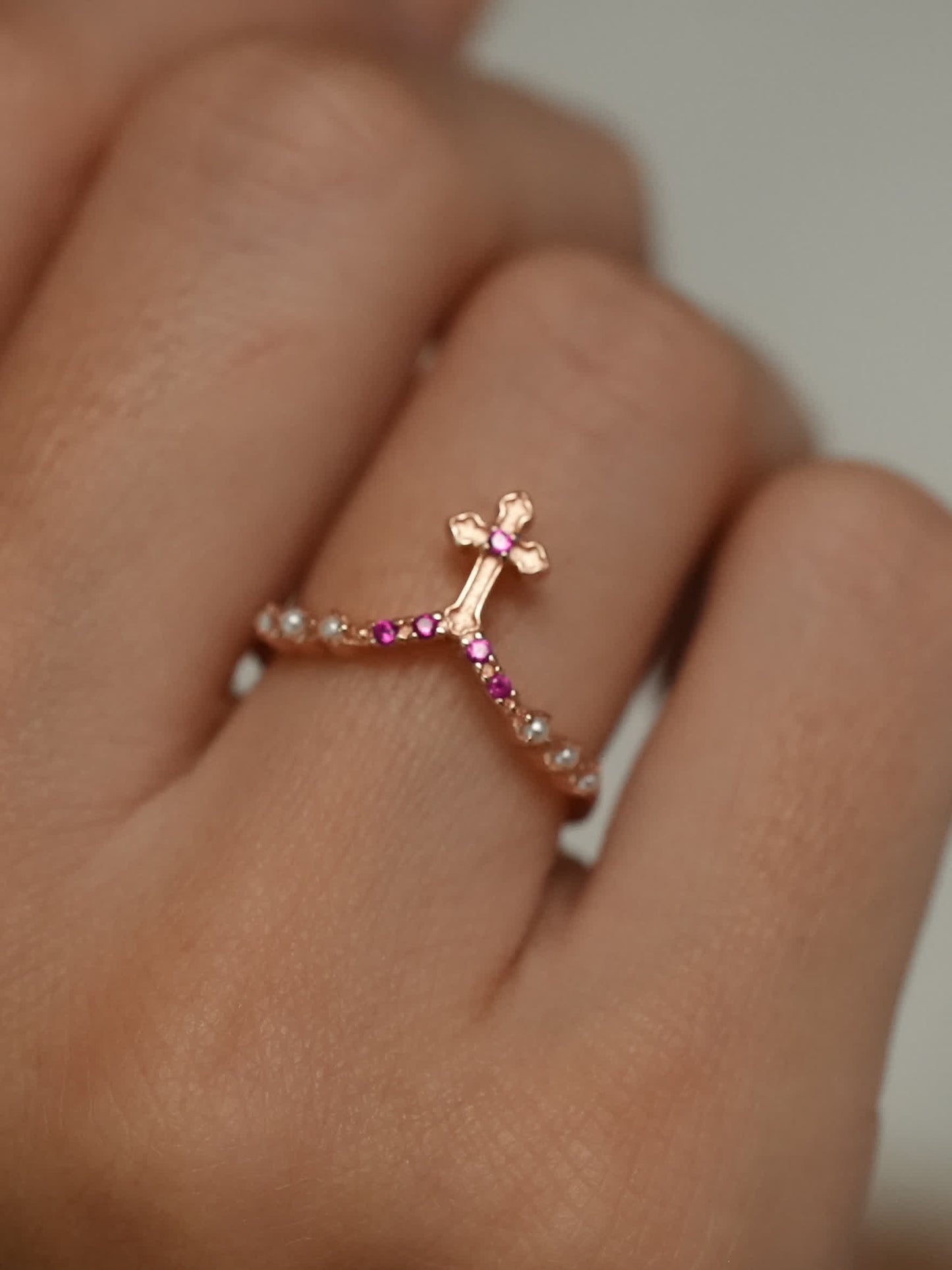 Rose gold vow ring with cross design worn on female hand, angled view