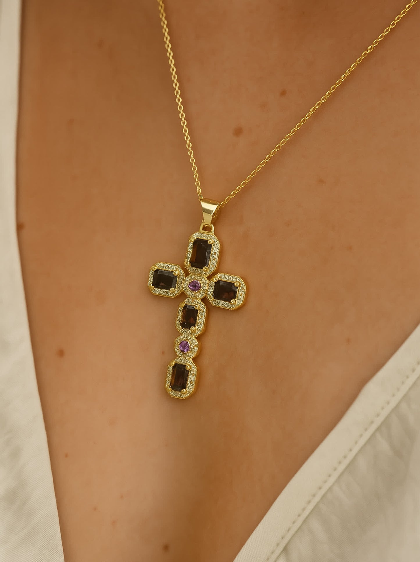 Model wearing the Faithstone zircon cross necklace, pendant centered at chest over a cream V-neck blouse