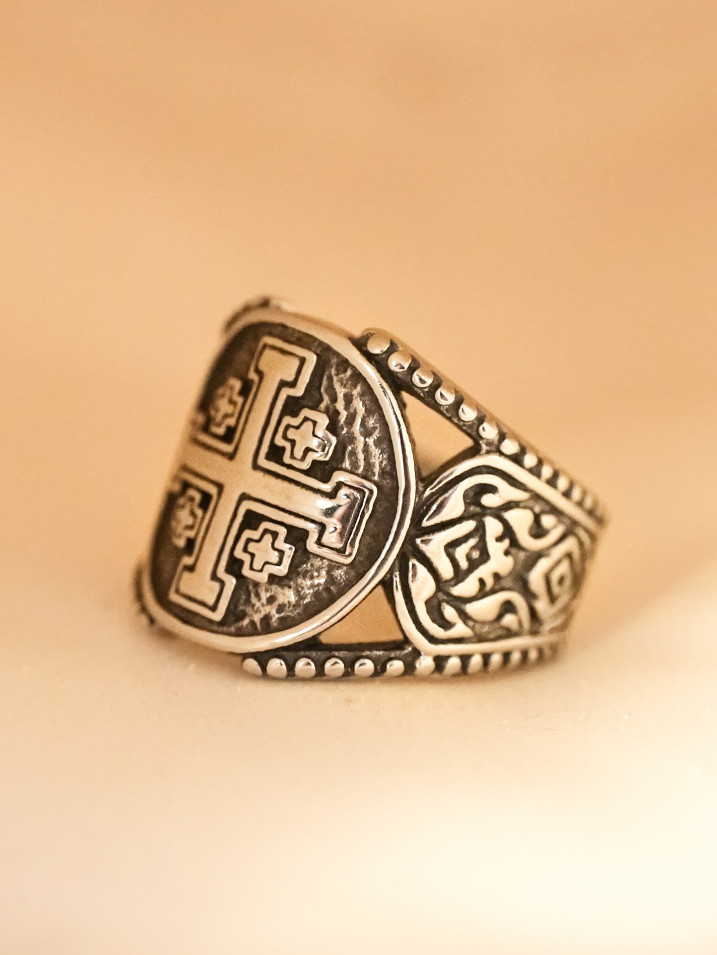 Side profile of the titanium steel ring against warm lighting, showcasing intricate etching and beaded edge