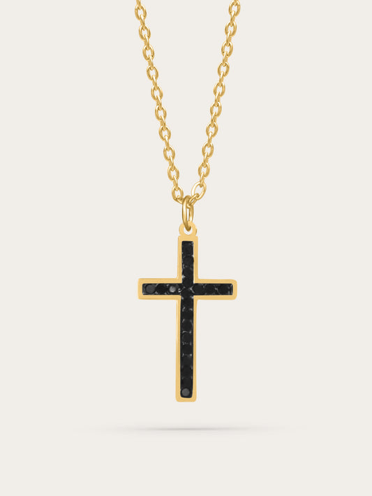 Gold cross necklace with black zircon stones displayed on light background