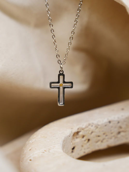 Necklace hanging against warm stone
Minimalist mustard seed cross pendant hanging over curved beige stone with soft shadows