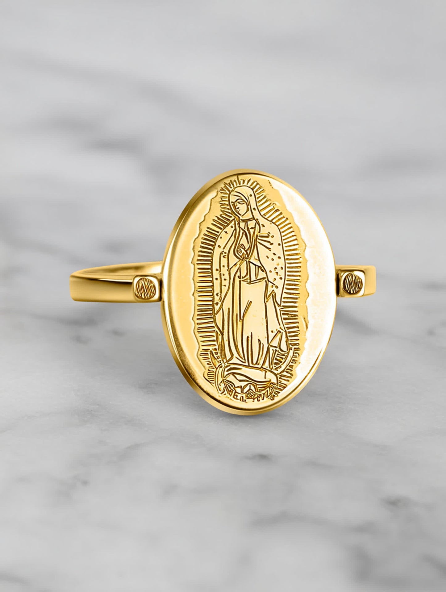 Close-up of the Our Lady ring on a marble surface, highlighting the detailed Virgin Mary engraving