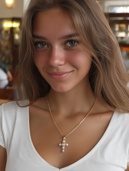 Young woman wearing elegant gold and pearl cross necklace with white top