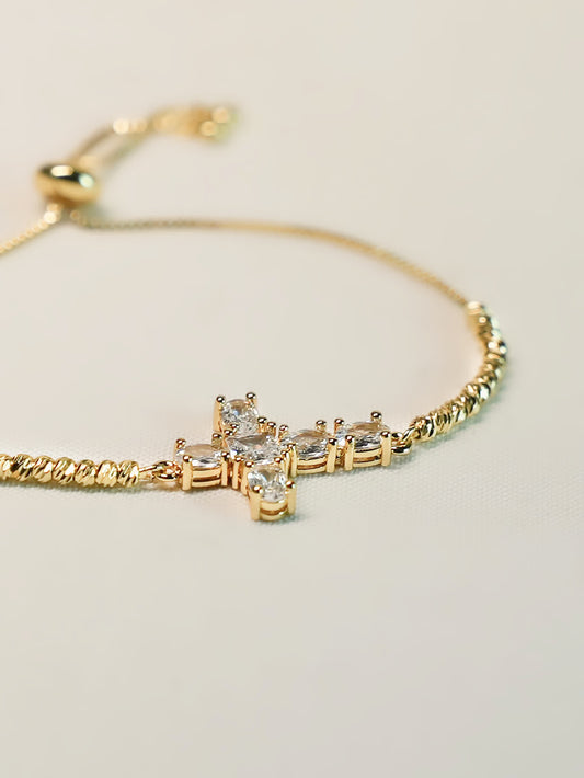 Studio photo of the Radiant Mercy Gold Cross Bracelet on a clean off-white background, showcasing the delicate construction and crystal cross design.