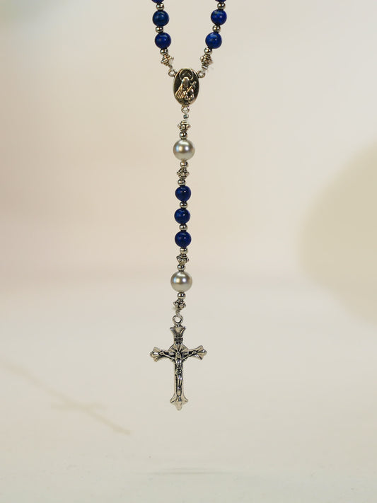 black lava rosary necklace with silver cross on neutral background