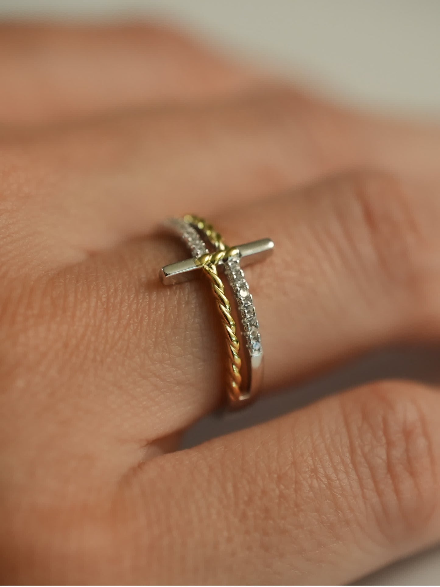 Lifestyle image of silver and gold cross wrap ring on model’s hand, showcasing spiritual and minimalist aesthetic
