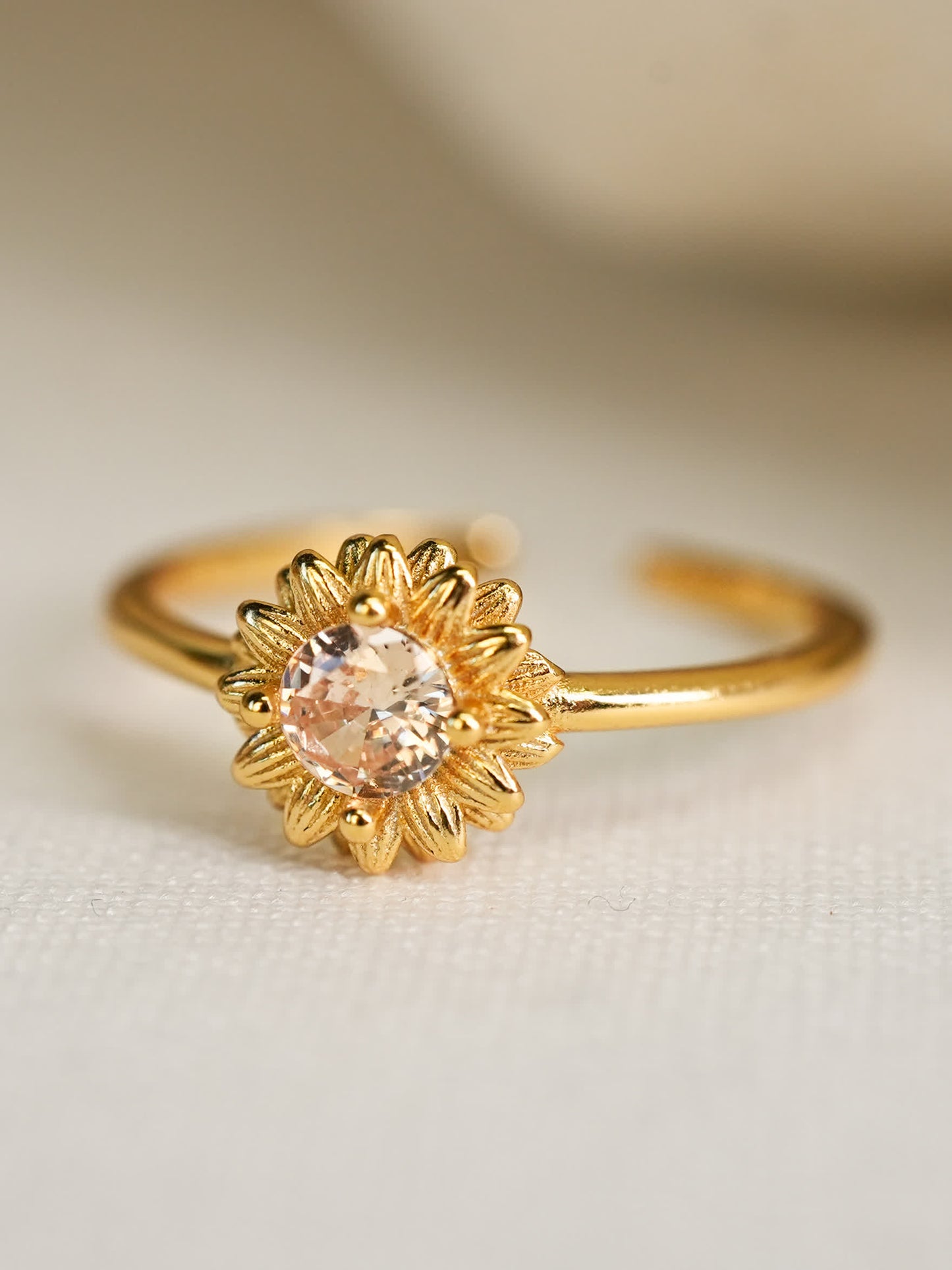 Side angle view of the sunflower-inspired Christian ring placed on a soft white surface, capturing its radiant sparkle and 18K gold finish