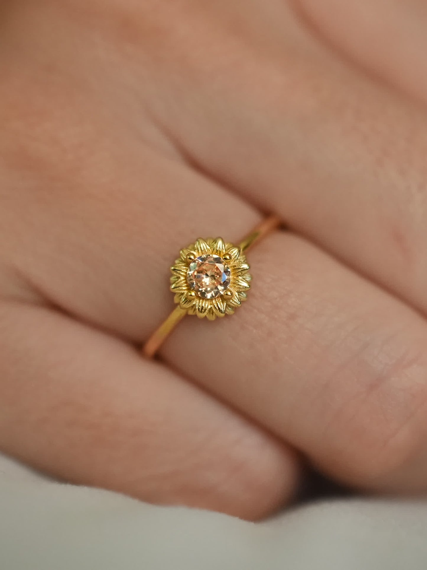 Hand shot displaying the Shine Forth Sunflower Ring on a model's finger, highlighting its feminine size and joyful floral design
