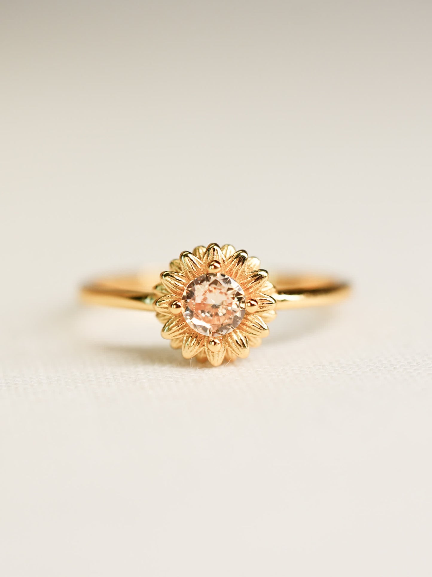 Front-facing image of the Shine Forth Sunflower Gold Ring with a round yellow zircon center and gold petal detailing on a neutral background