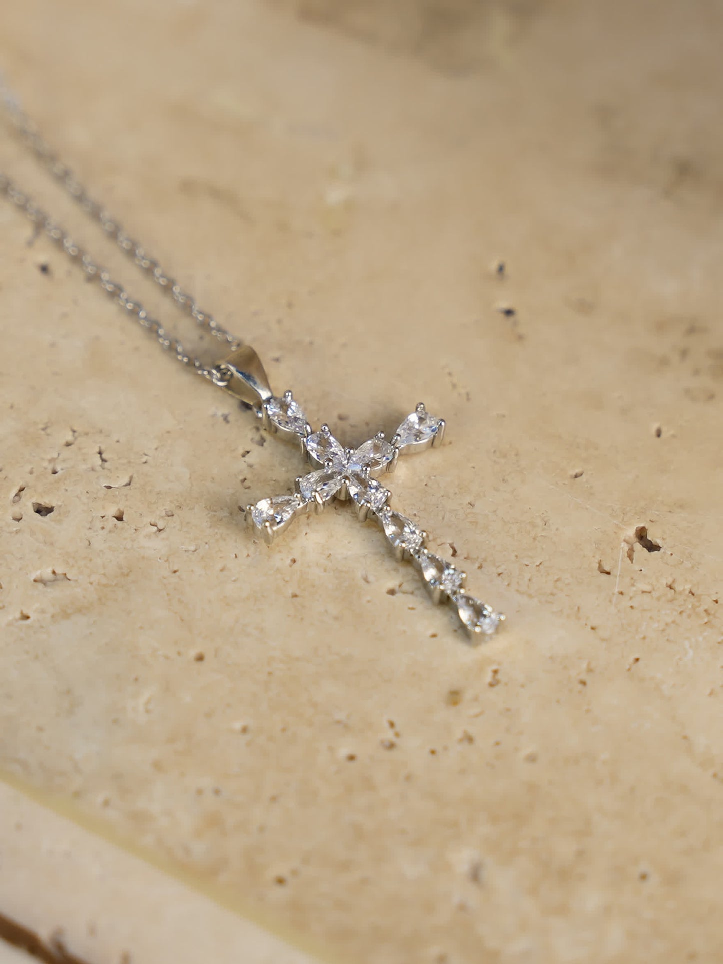Flat-lay photo of the pendant on marble surface, showing teardrop crystal detailing and chain design