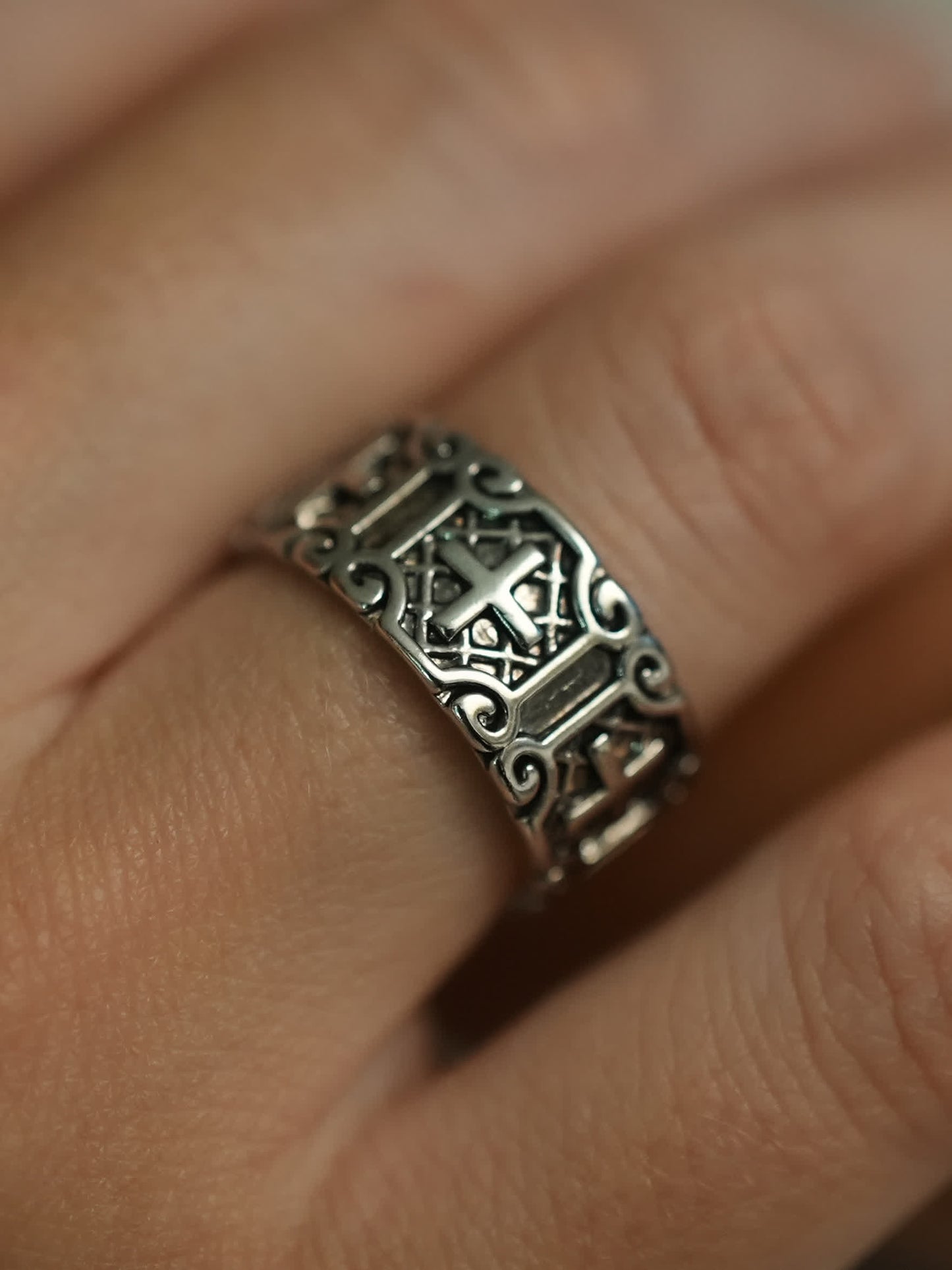 Carved Christian cross band ring worn on male hand, close-up detail