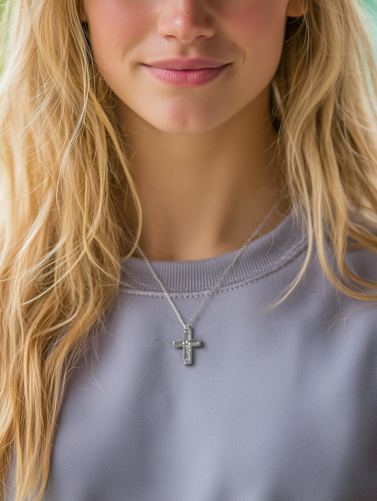 Woman wearing silver-tone baguette cross necklace over a soft lavender top