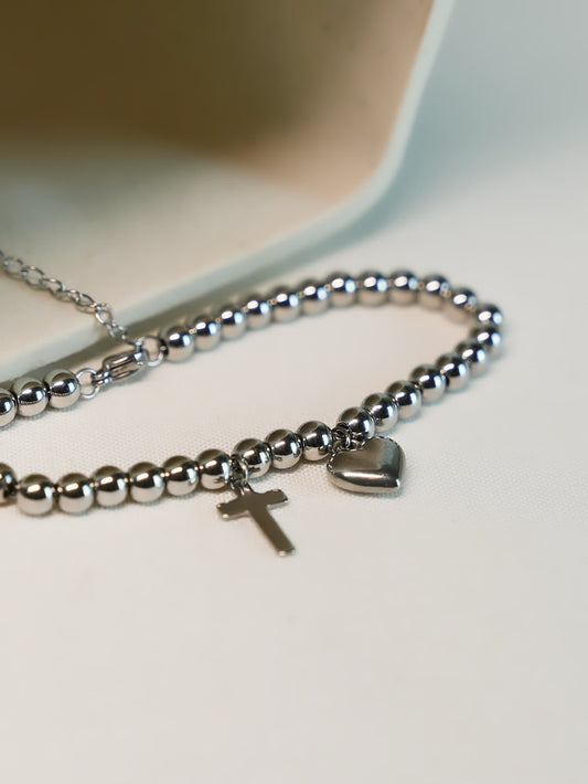 Studio image of the Pray Through It Cross Charm Bracelet on a soft white background, highlighting the silver-toned finish and delicate double charm details.