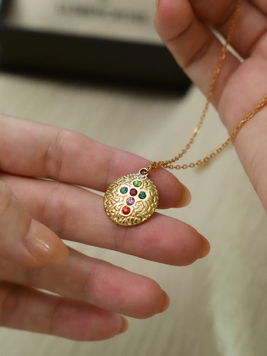 Hand holding Covenant Light gemstone cross necklace with rainbow zircon design