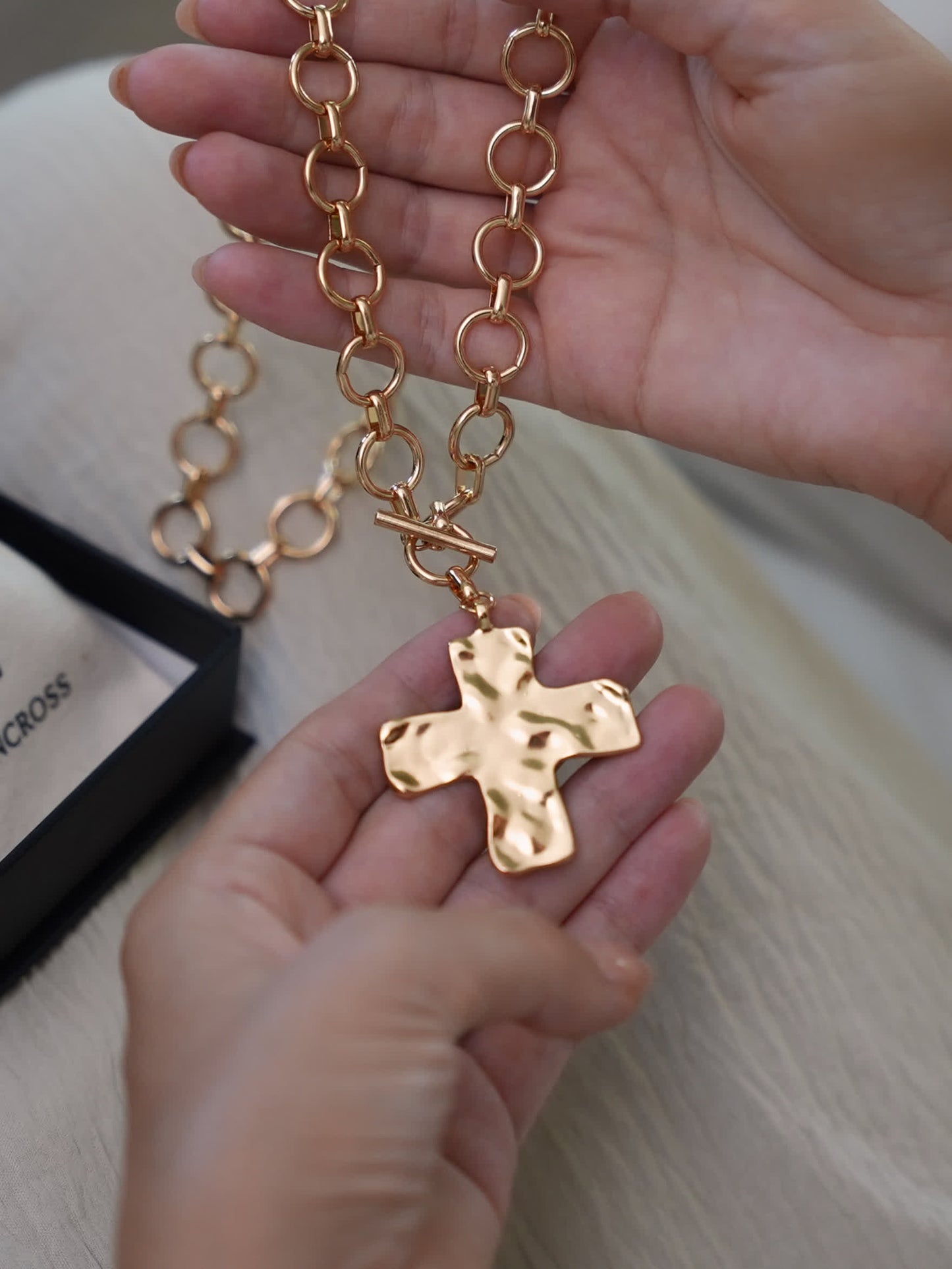 Hand holding chunky Christian cross necklace with oversized links, shown with Lumencross packaging