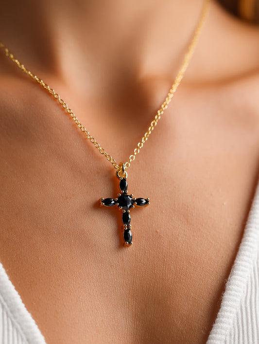 Close-up of the black zircon cross necklace worn by a woman in a white top