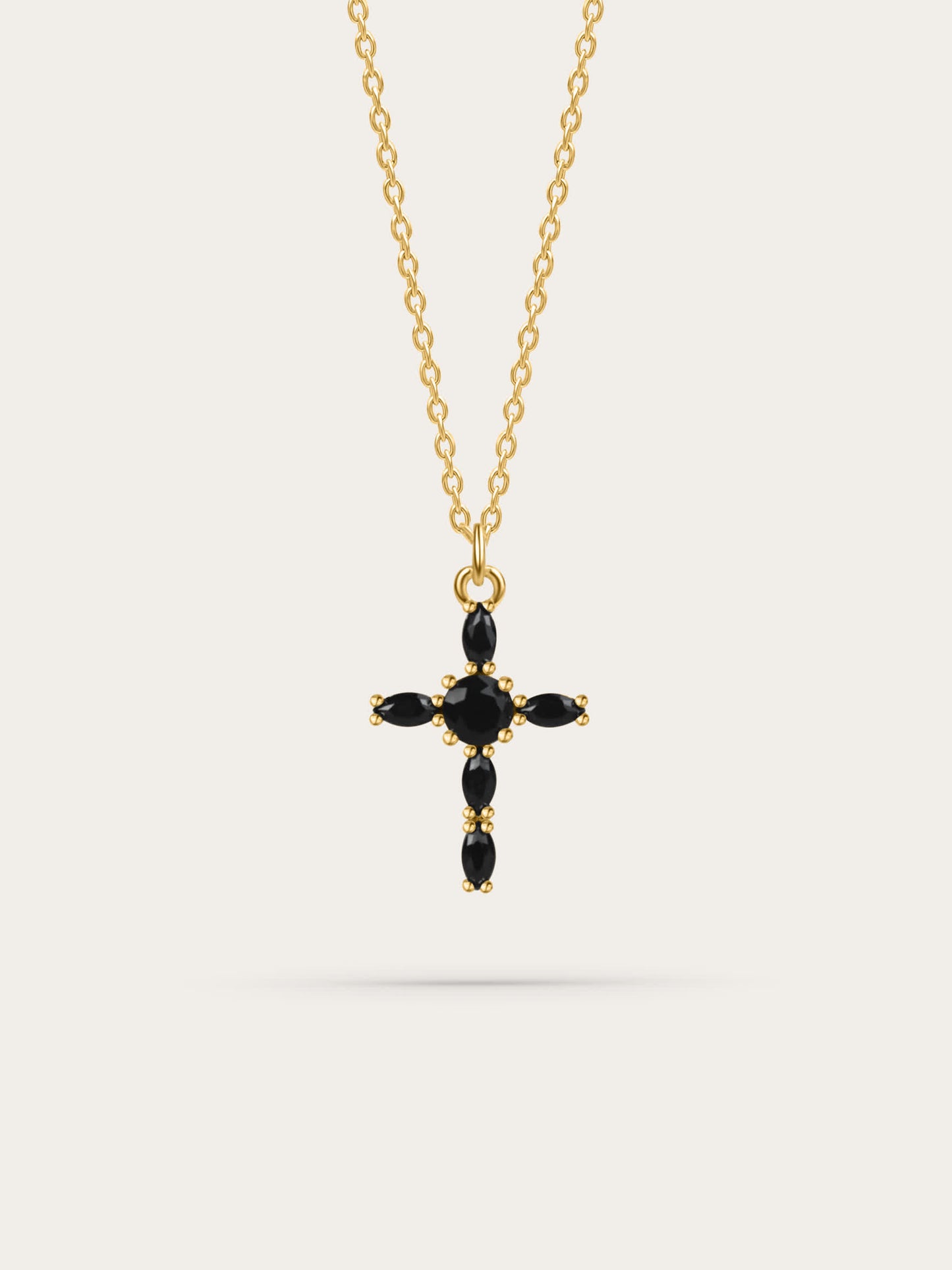 Studio photo of a black zircon marquise gold cross necklace on white background