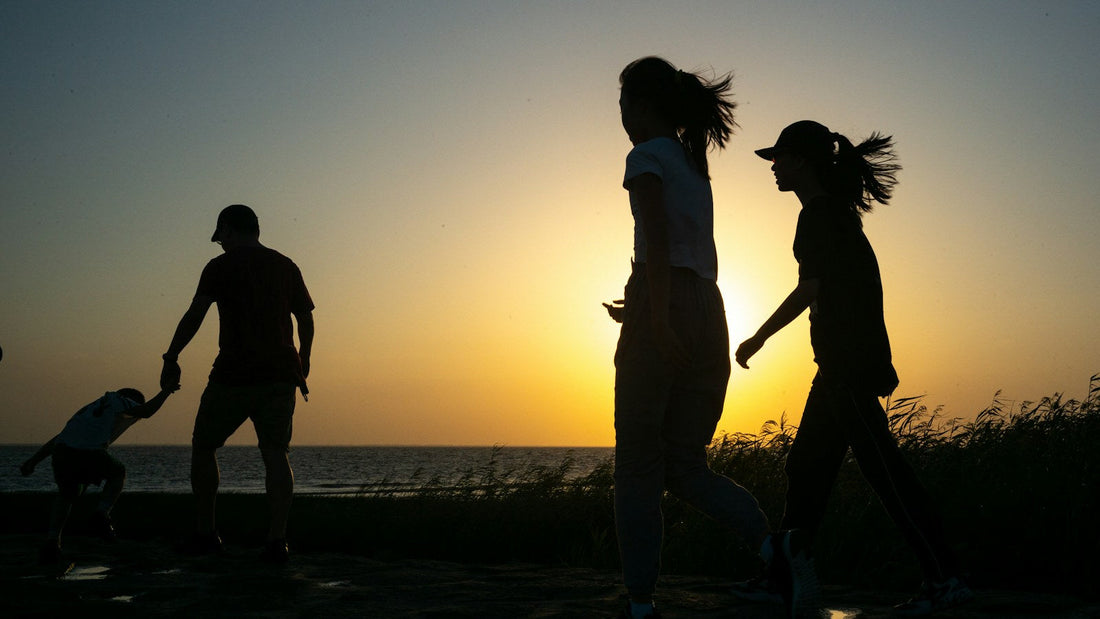 Silhouetted family walking together by the water at sunset
