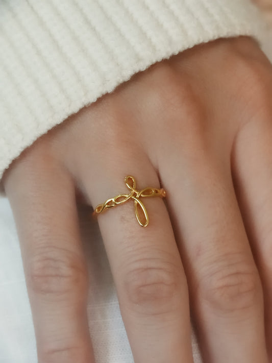 Gold openwork cross ring worn on hand with cozy white sweater, showcasing elegant minimalist design