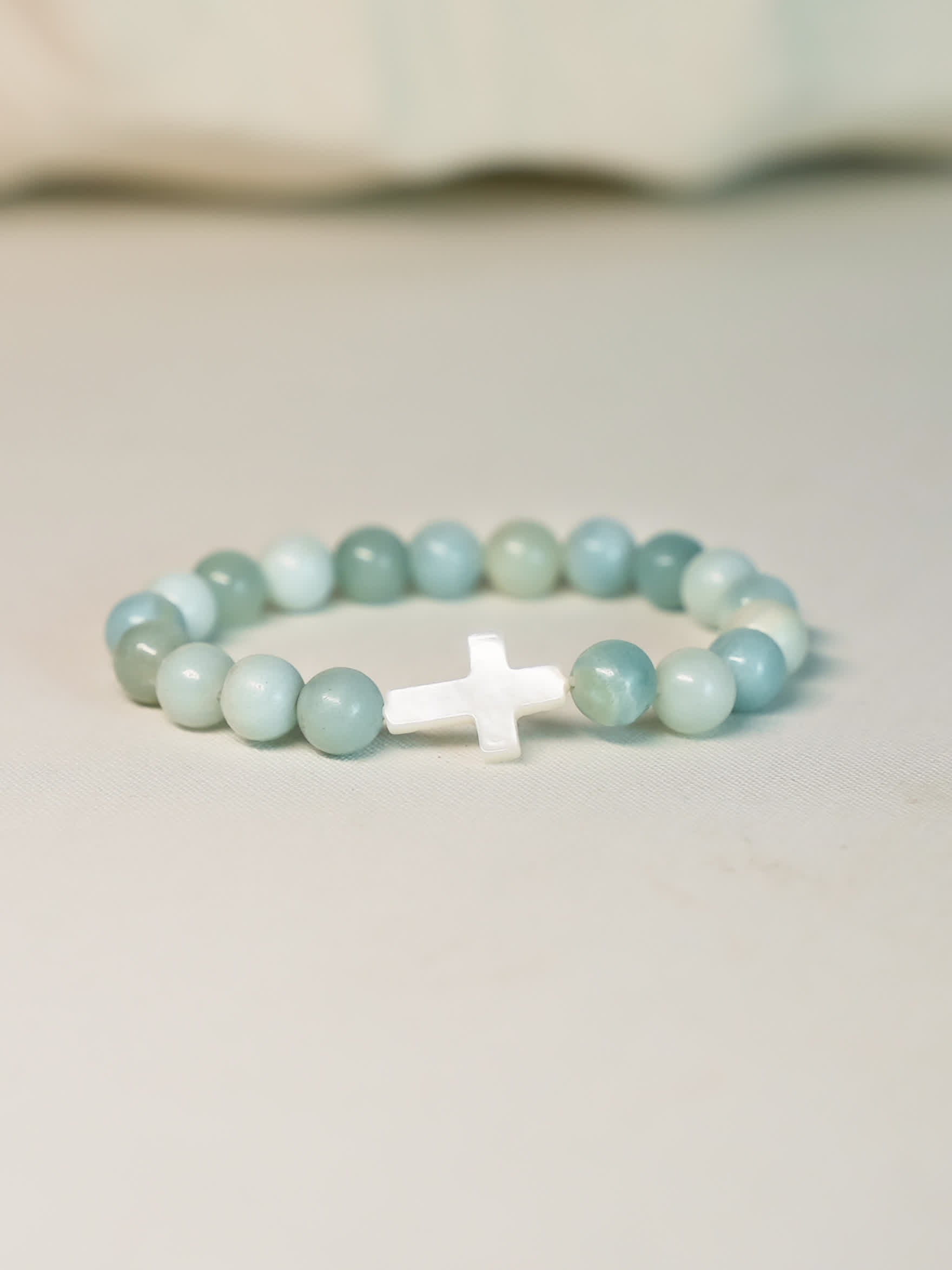 Front-facing product shot of the Sea of Grace Cross Bracelet on a clean neutral background, showcasing the cross and ocean-toned gemstone beads.