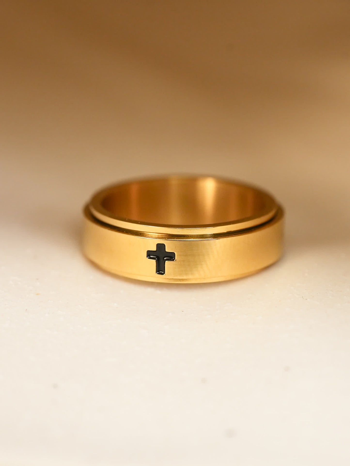 Close-up of gold-plated Christian spinner ring, black engraved cross clearly visible