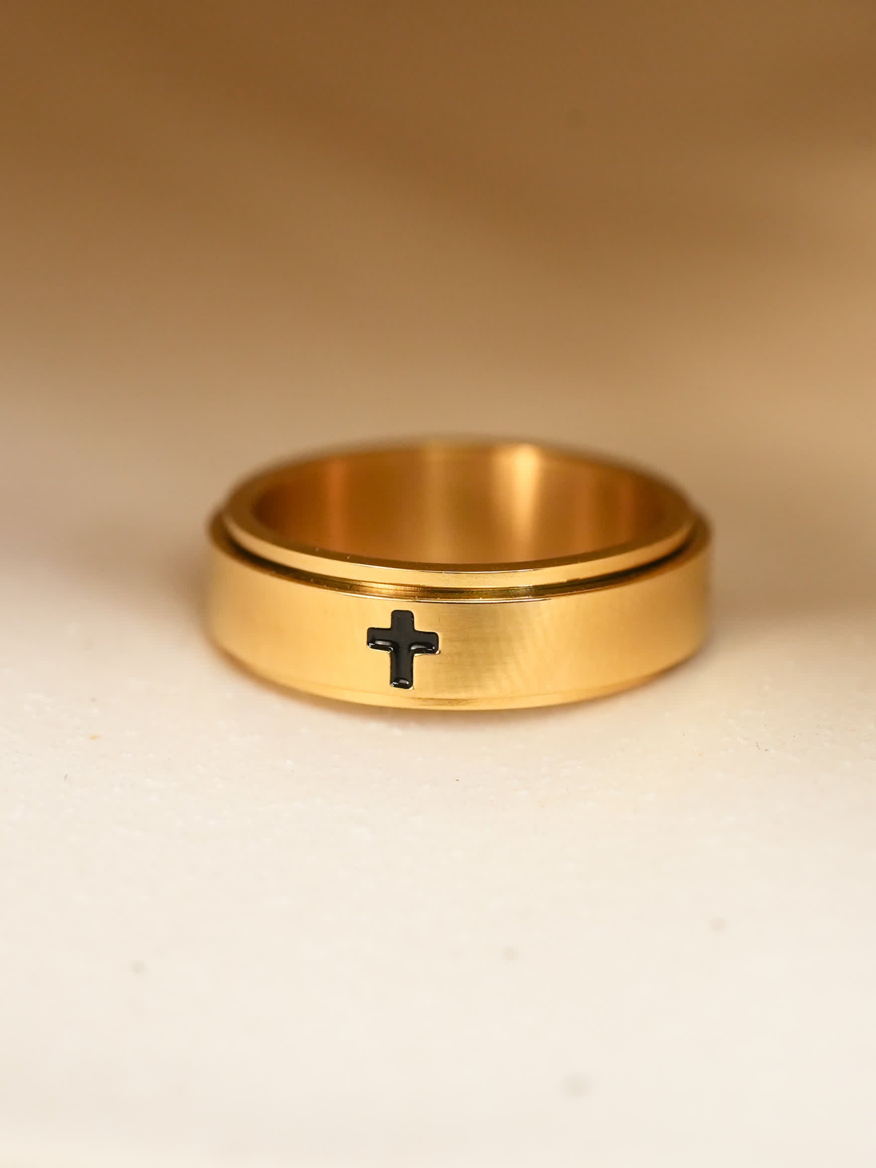 Close-up of gold-plated Christian spinner ring, black engraved cross clearly visible