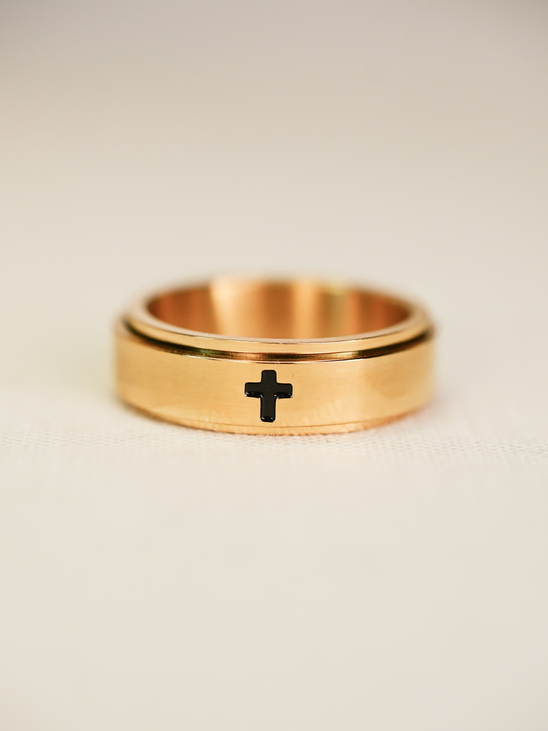 Angled view of rotating gold worry ring, featuring minimalist cross design