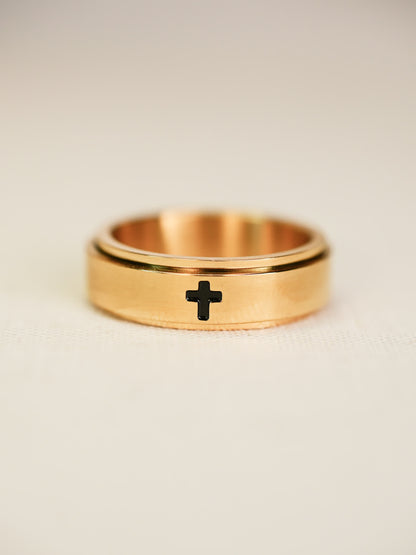 Angled view of rotating gold worry ring, featuring minimalist cross design