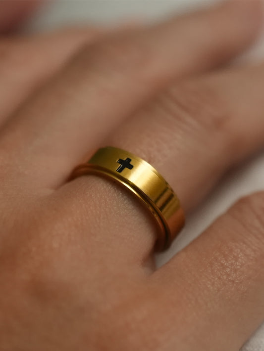 Gold cross spinner ring on male hand, reflecting polished 18K gold with subtle rotation