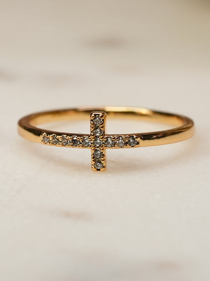 Side angle of the Anointed Radiance ring on a soft background, emphasizing the curved gold band and radiant pavé cross
