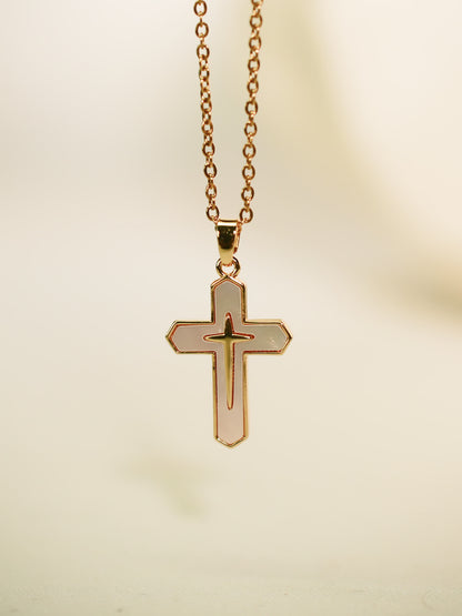 Vertical studio image of the gold enamel cross pendant hanging against a soft neutral backdrop