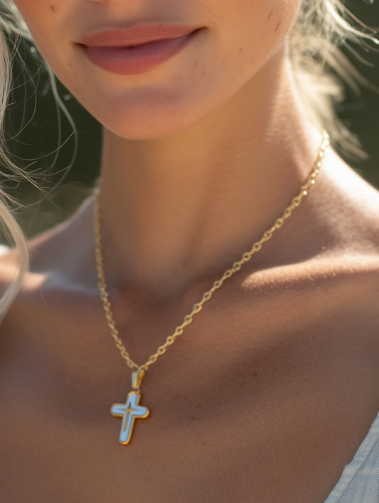 Close-up lifestyle shot of a woman wearing the white enamel cross necklace outdoors
