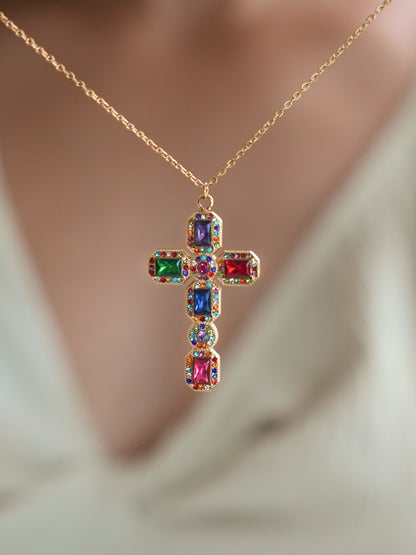 Baroque multistone cross pendant worn by a model in a v-neck white top, highlighting the bold and colorful gemstone arrangement with elegant 18K gold detailing.