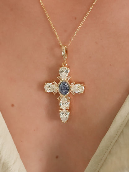Blue gemstone and crystal cross necklace worn on a woman's chest, showcasing the necklace's size and shine against skin