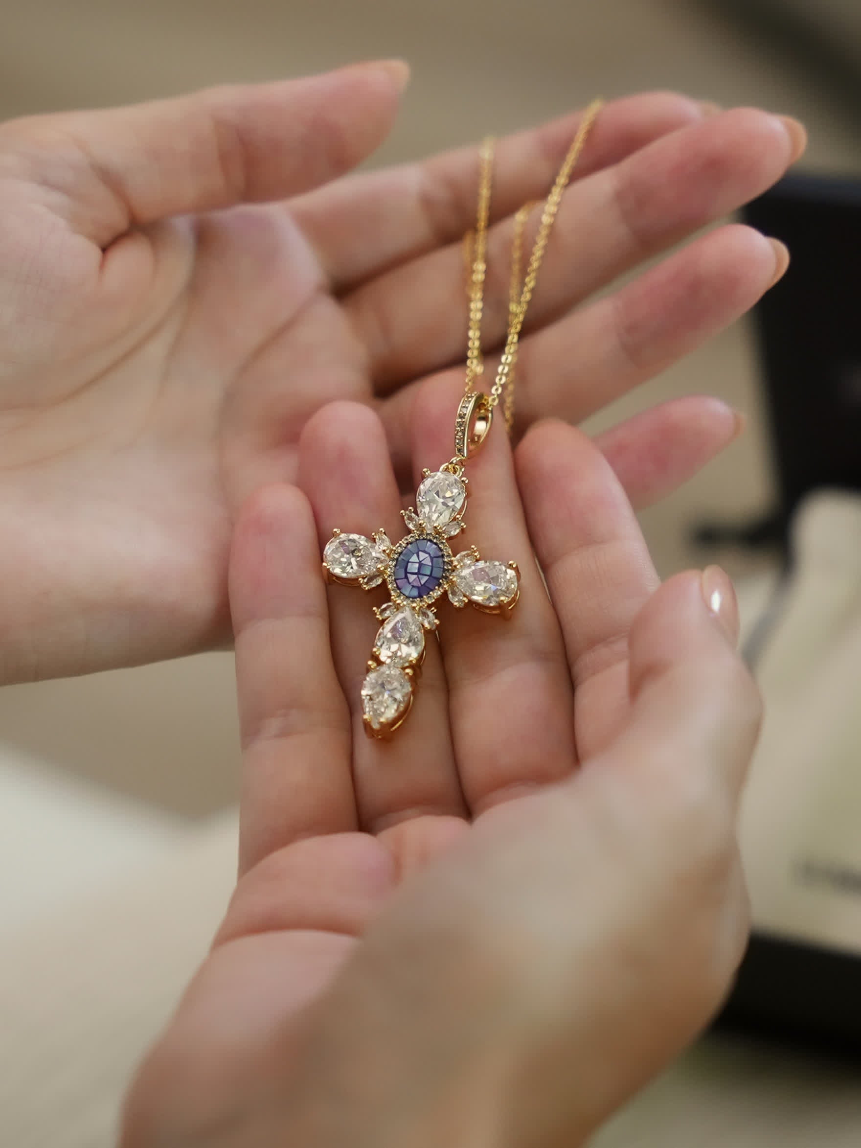 Close-up of the ornate Victorian cross pendant resting on a stone surface, showing pear-cut crystals and detailed gold setting