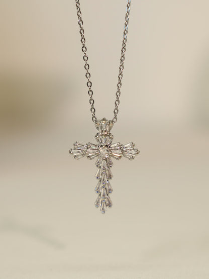 Hanging pendant view: Vertical shot of the silver cross necklace hanging, showcasing teardrop and baguette zircon detail