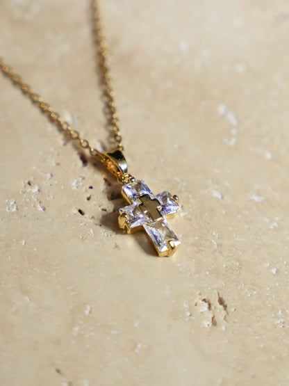 Artistic shot of the cross necklace on warm travertine stone with natural shadows and highlights