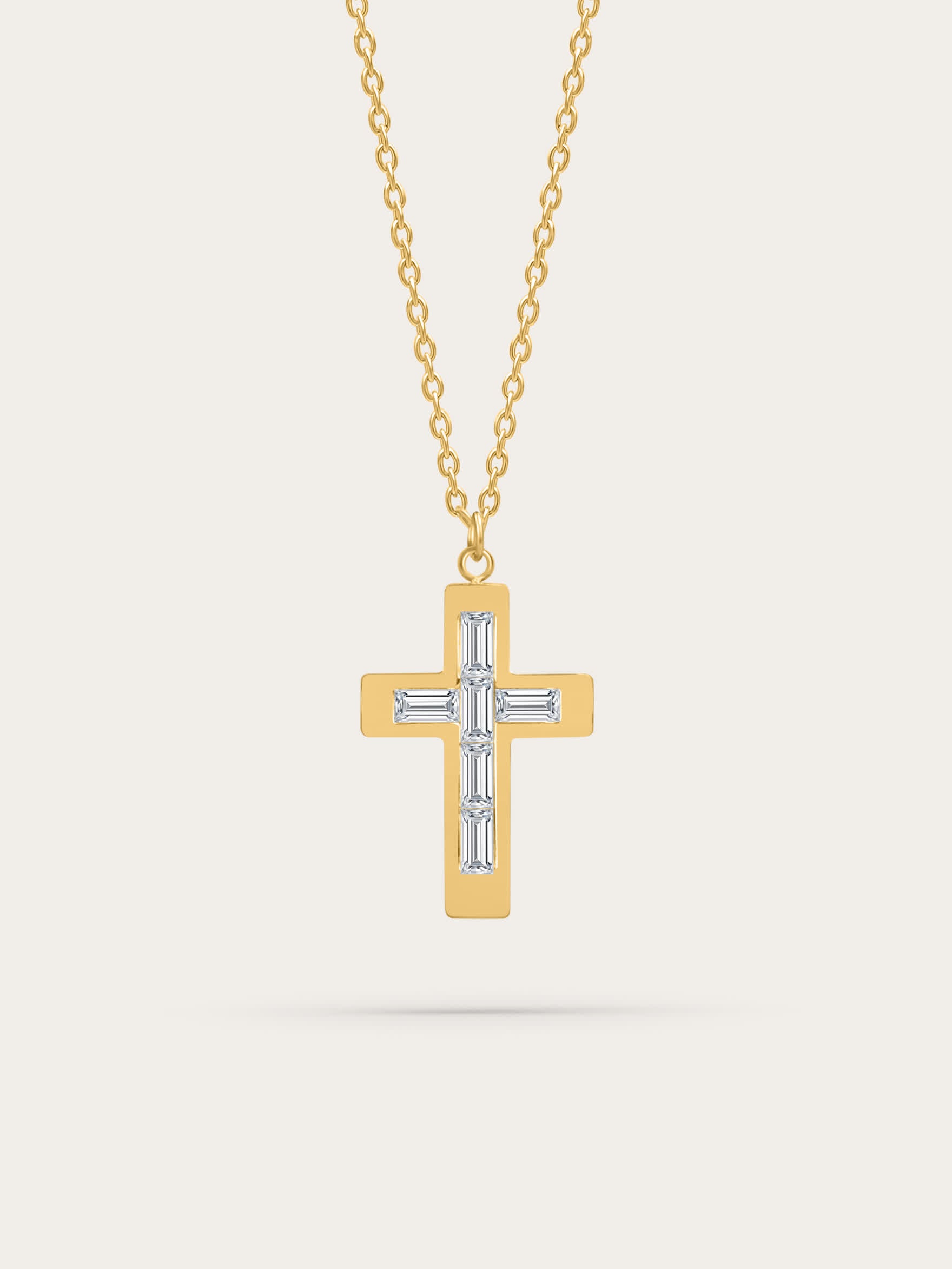 Gold cross necklace with baguette-cut zircon stones on neutral background