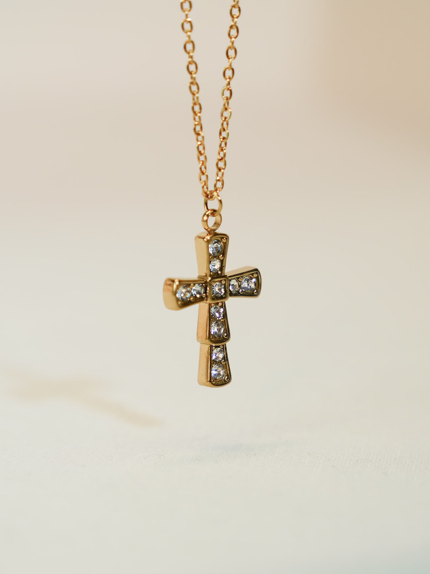 Elegant close-up of the gold cross pendant floating mid-air, highlighting the symmetry and shimmer of the crystals