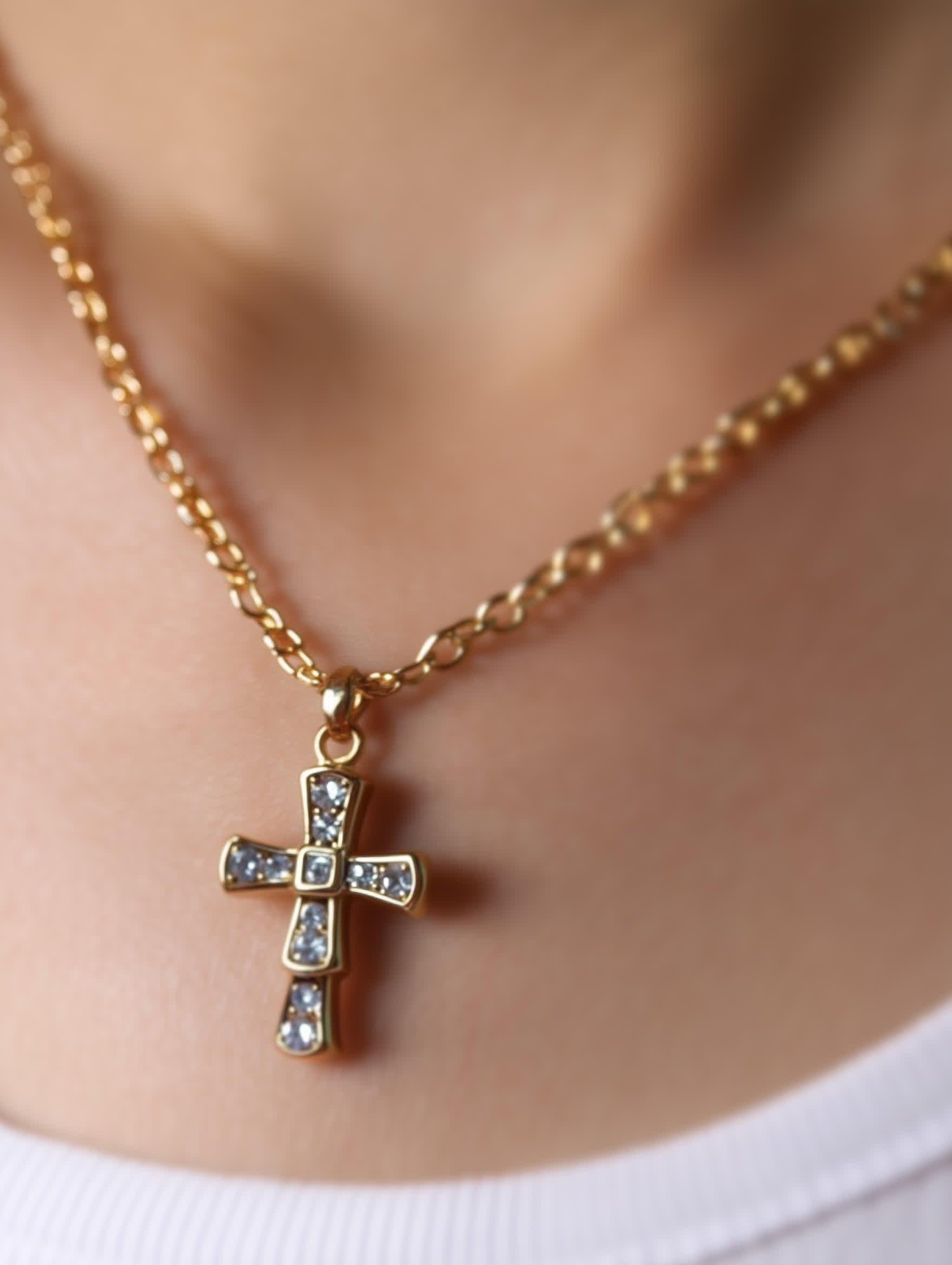 The Quiet Radiance Crystal Cross Necklace worn by a model with a white top, showcasing its size and refined design against the neckline