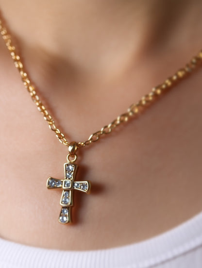 The Quiet Radiance Crystal Cross Necklace worn by a model with a white top, showcasing its size and refined design against the neckline